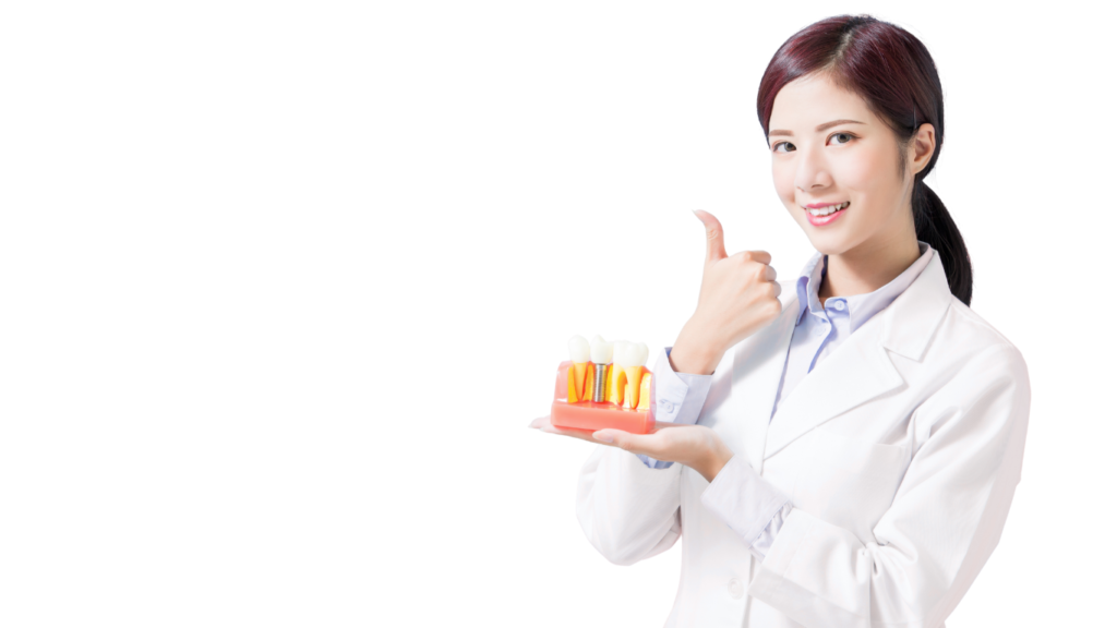A smiling female dentist in a lab coat holding a dental implant model and giving a thumbs up, representing high-quality dental care in Vietnam.