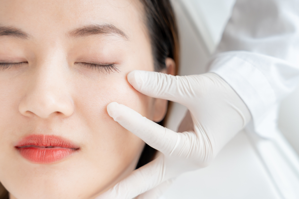 A consultation featuring a specialist in white gloves examining a patient's face to determine cosmetic surgery cost in Vietnam for facial rejuvenation and aesthetic procedures.