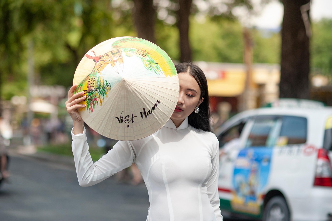 A woman in a white Ao Dai holding a traditional Vietnamese conical hat (Non La) offering medical concierge in Asia