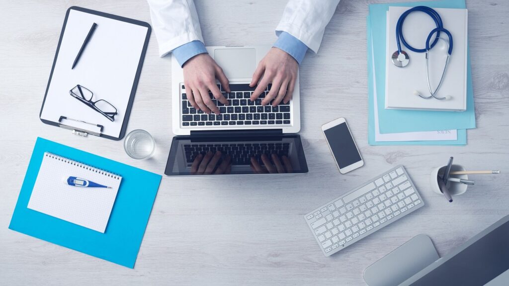 Travel and Medical Insurance for Surgery Abroad in Asia 1 A medical professional's organized workspace with a laptop and stethoscope, representing the streamlined digital consultation and contact process at East Bridge Care.