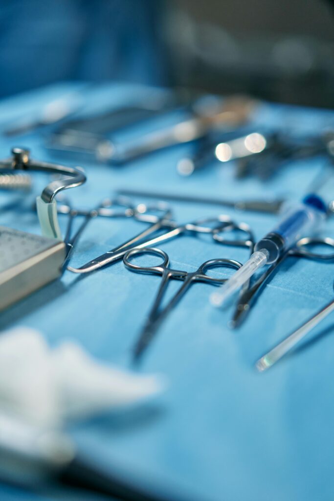 Close-up of surgical equipment including scissors and syringe on a blue sterile cloth, emphasizing healthcare tools.
