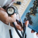 A close-up of a hand holding a stethoscope and a Vietnam travel guide, symbolizing medical tourism in Vietnam