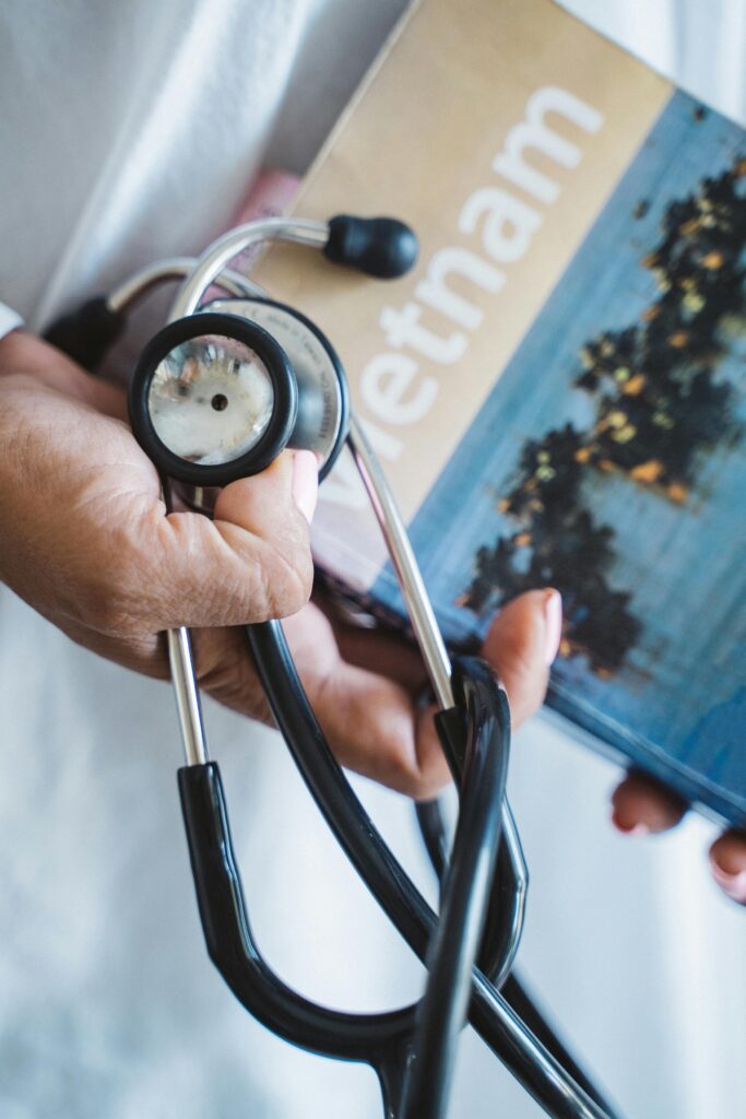 A close-up of a hand holding a stethoscope and a Vietnam travel guide, symbolizing medical tourism in Vietnam