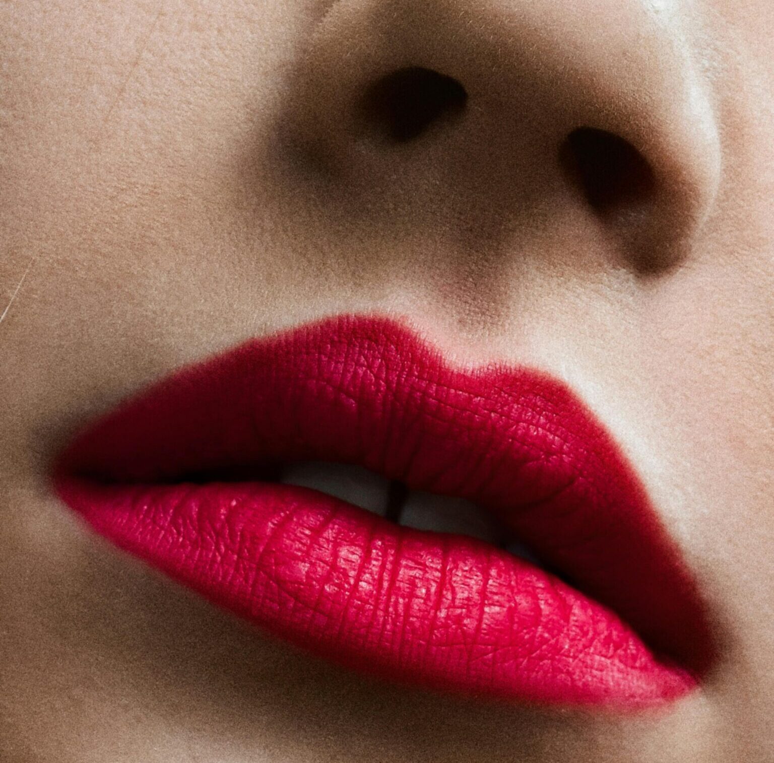 Detailed close-up of a woman's face showcasing vibrant red lips and subtle eye makeup.