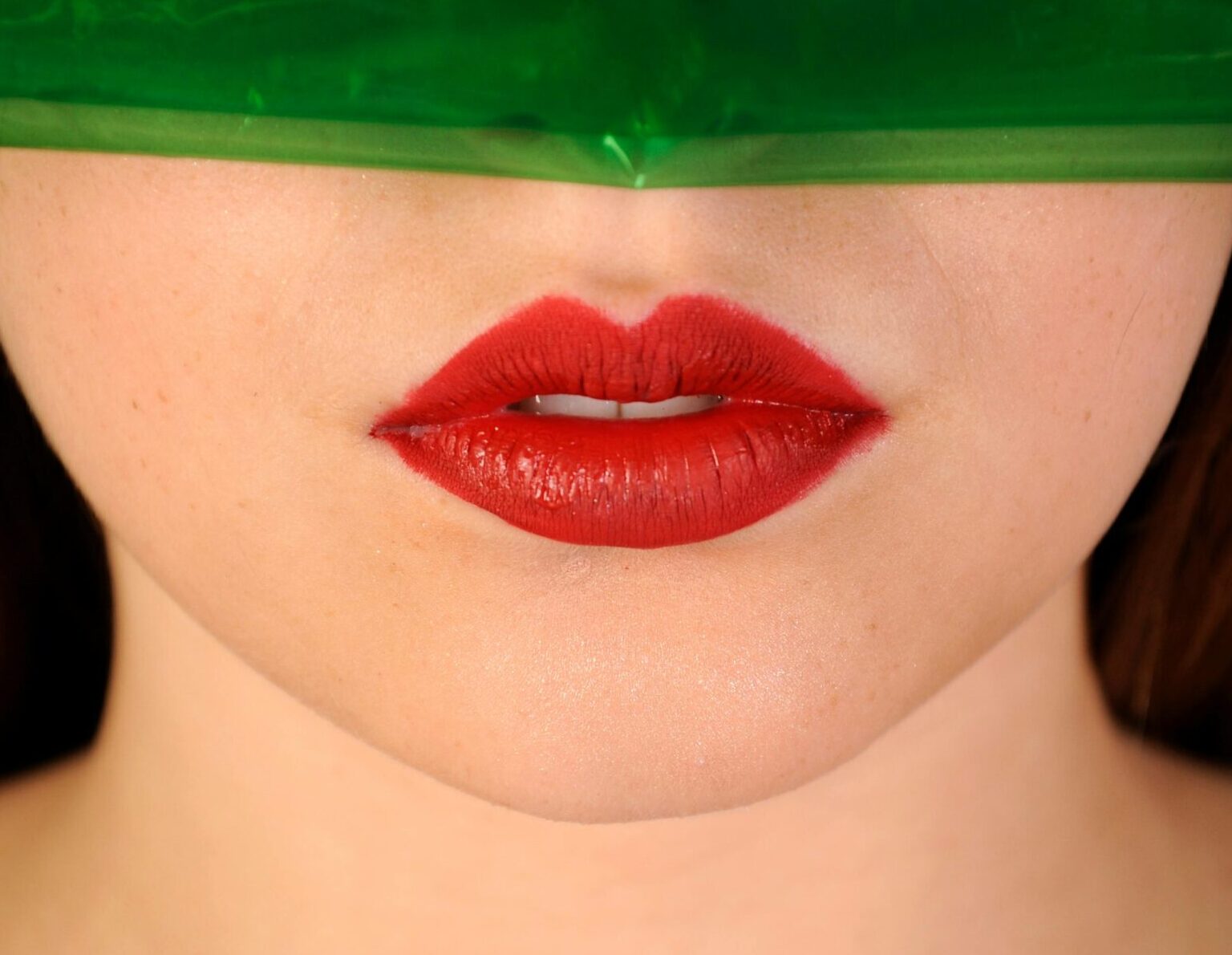 Artistic close-up photo of red lips with a green overlay, creating a vibrant and modern look.
