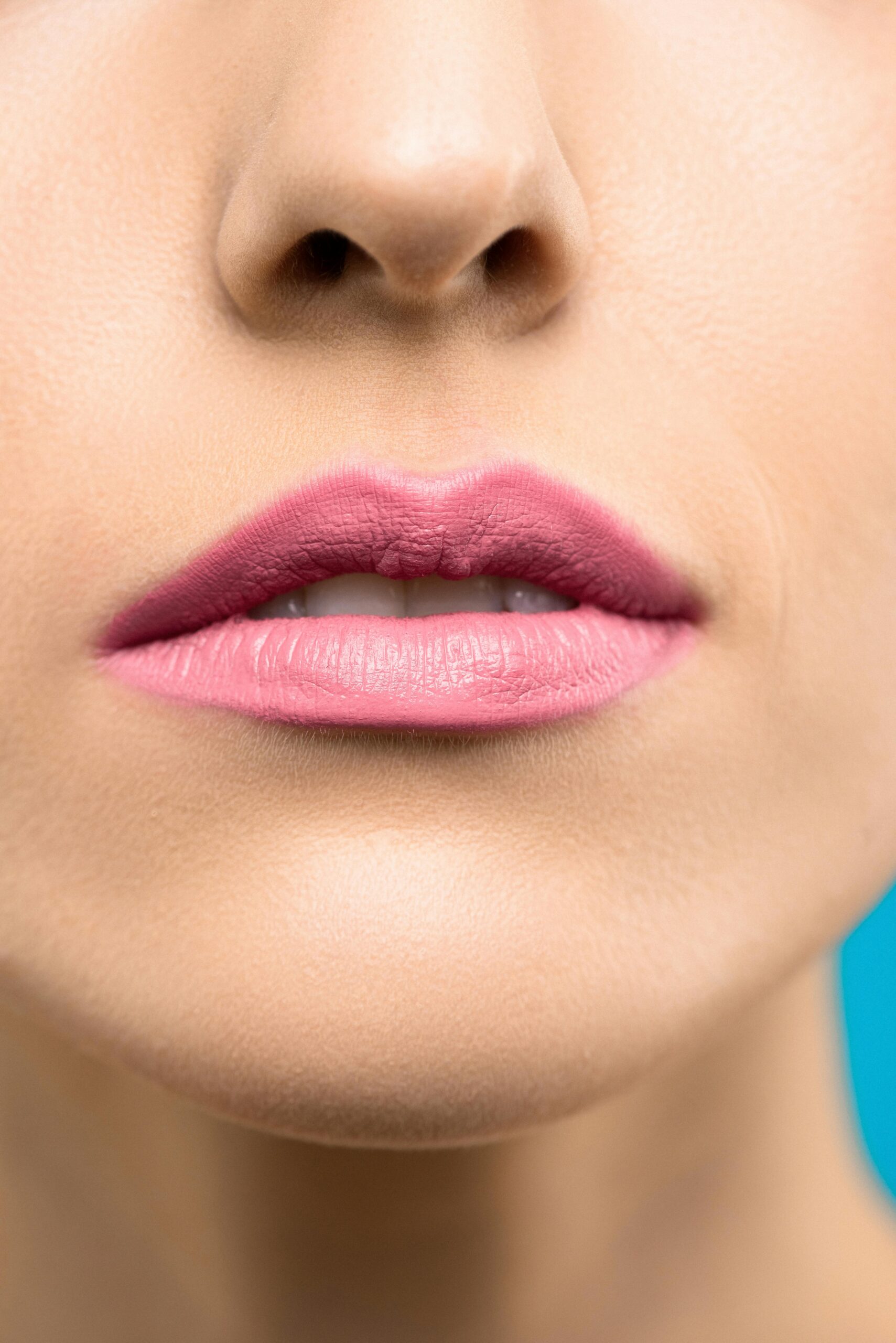 Close-up of a woman's lips with pink lipstick, highlighting beauty and minimalism.