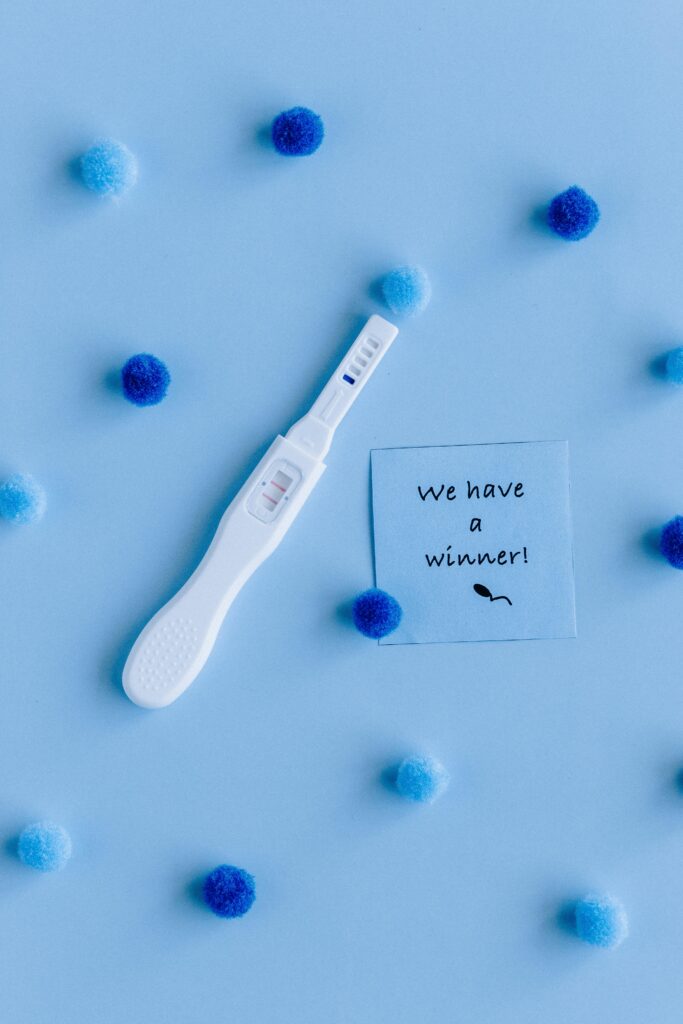 Positive pregnancy test surrounded by pom-poms on blue background with 'We have a winner!' note, ivf in Vietnam