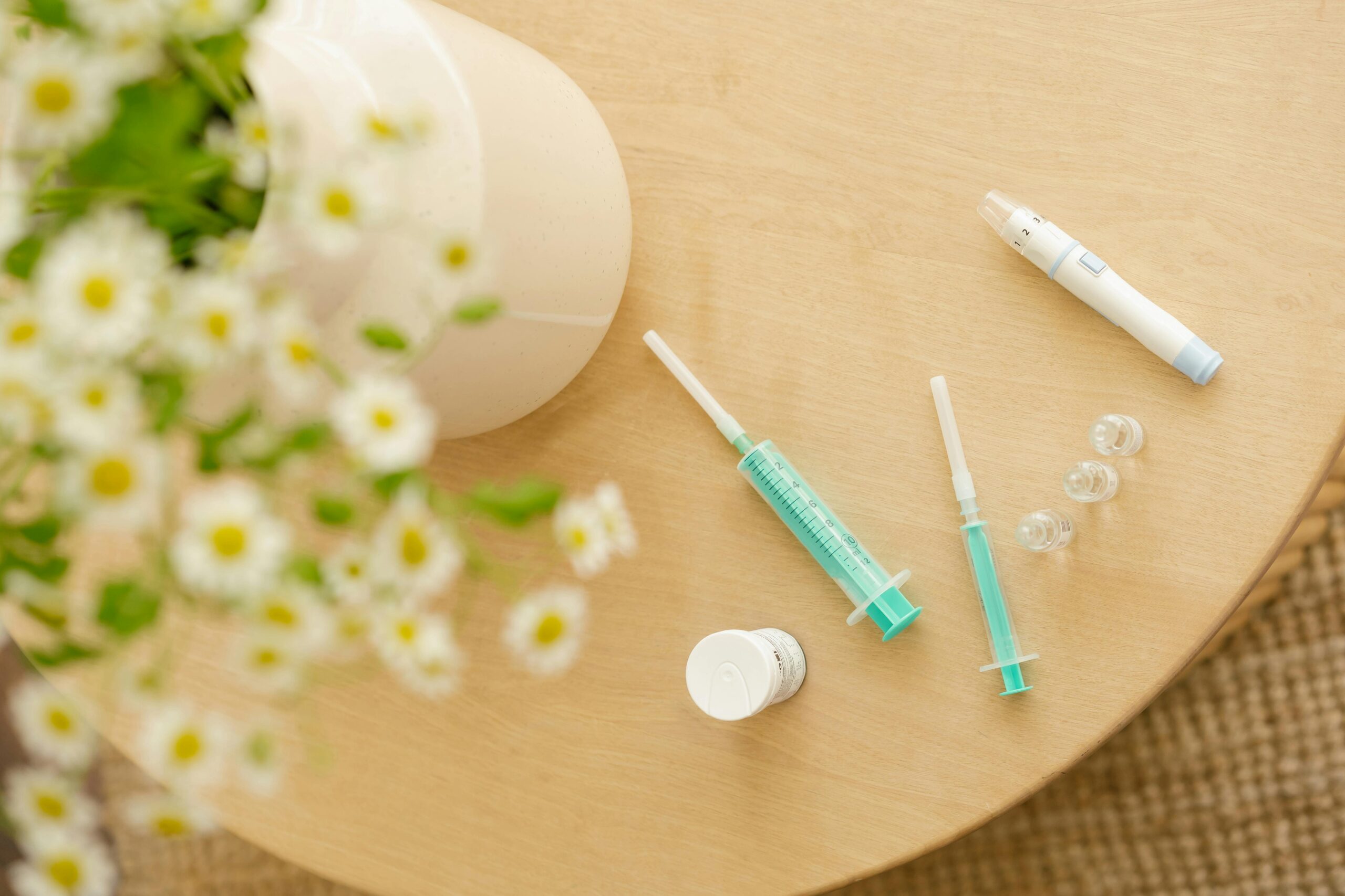 Top view of diabetic care kit with syringes and injector pen on a wooden table with flowers, ivf in vietnam.